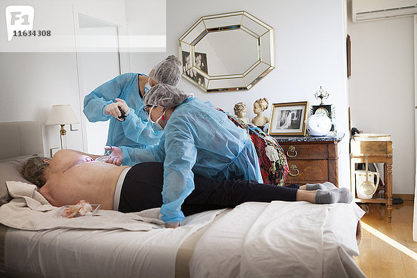 Reportage über einen häuslichen Pflegedienst in Savoie  Frankreich. Eine Krankenschwester und eine Hilfskraft legen einen VAC-Therapie-Verband auf eine Pulmonektomie.