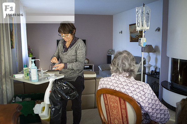 Reportage über einen häuslichen Pflegedienst in Savoie  Frankreich. Eine Krankenschwester wechselt bei einem Krebspatienten den Beutel für parenterale Ernährung.