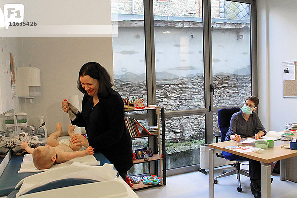 Reportage in einem französischen Mütter- und Kinderschutzzentrum in Châteaubriant  Frankreich. Konsultation mit einem Kinderarzt. Entkleiden des Kindes.