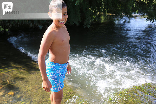 Junge watet in einem Fluss.