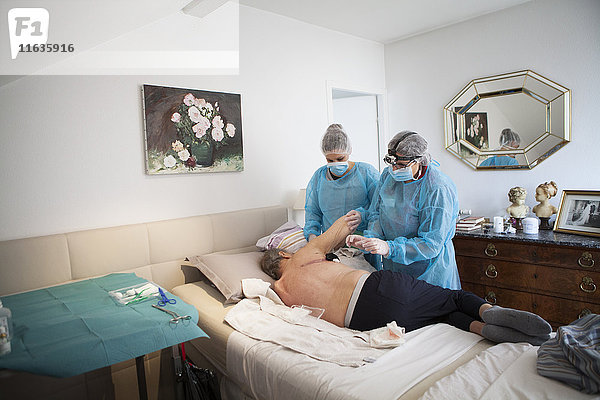 Reportage über einen häuslichen Pflegedienst in Savoie  Frankreich. Eine Krankenschwester und eine Hilfskraft legen einen VAC-Therapie-Verband auf eine Pulmonektomie.