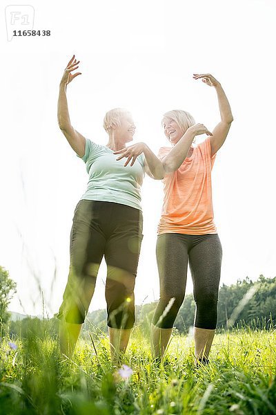 Zwei Frauen trainieren mit erhobenen Armen.