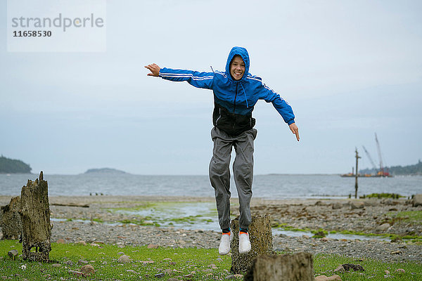 Teenager  der vom Baumstumpf springt  Pacific Rim National Park  Vancouver Island  Kanada