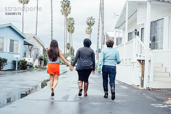 Rückansicht einer Mehrgenerationen-Familie in voller Länge  die auf der Straße geht und sich an den Händen hält