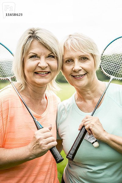 Zwei Frauen halten lächelnd Badmintonschläger.