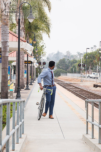 Junger Geschäftsmann Radfahrer blickt vom Bahnsteig zurück