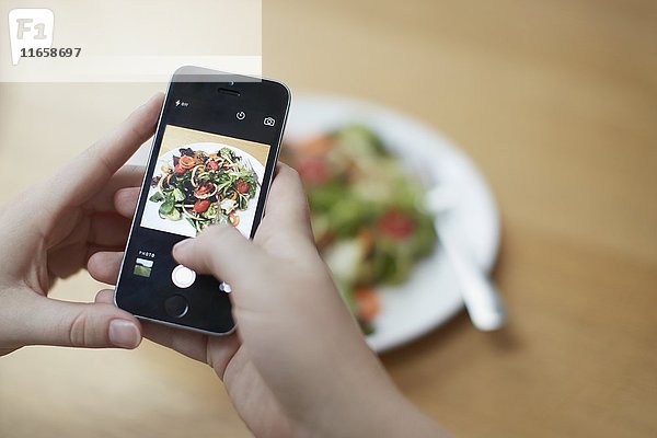 Frau  die mit ihrem Smartphone ein Foto von einem Lebensmittel macht und den Kaloriengehalt überprüft.