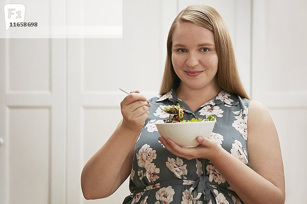 Junge Frau isst Schüssel mit Salat.