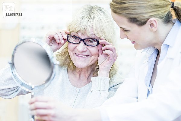 Optikerin berät eine ältere Frau in einem Optikerladen.