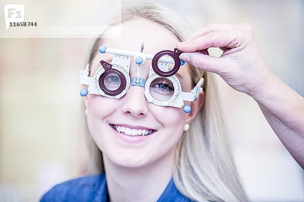 Porträt einer fröhlichen jungen Frau bei einer Augenuntersuchung in einem Optikergeschäft  Nahaufnahme.