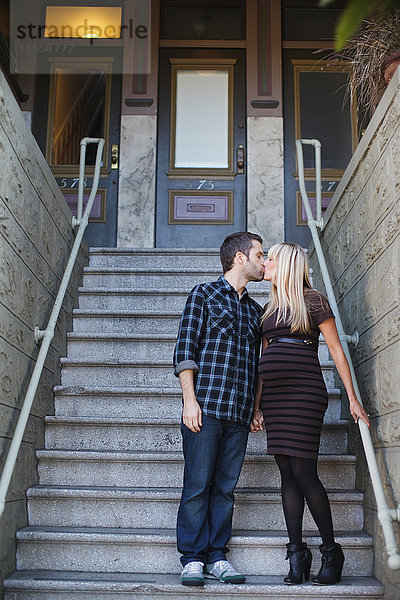 Schwangere mittlere erwachsene Frau küssend Freund außerhalb des Hauses Treppe
