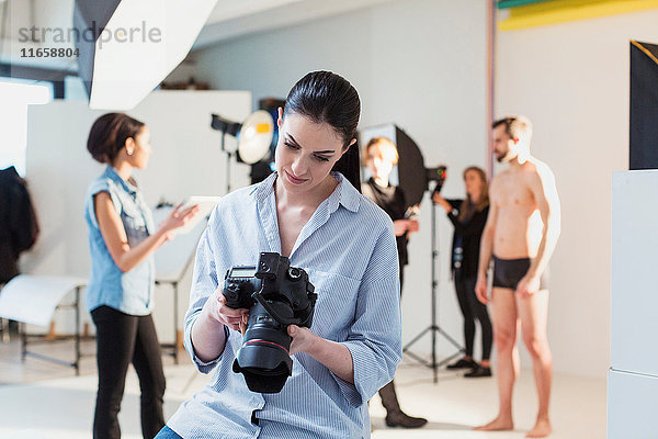 Junge Fotografin bespricht Aufnahme mit digitaler Spiegelreflexkamera im Fotostudio