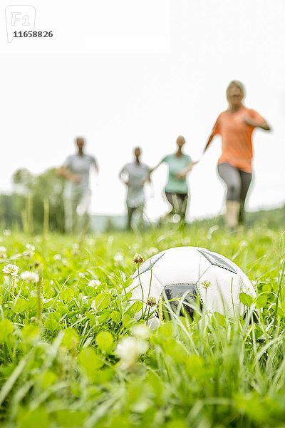 Eine Gruppe von Menschen spielt Fußball im Gras.