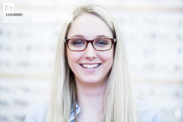 Porträt einer Frau  die in einem Optikergeschäft eine Brille ausprobiert.