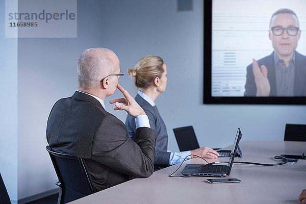 Geschäftsmann und -frau beobachten Büro-Telefonkonferenz