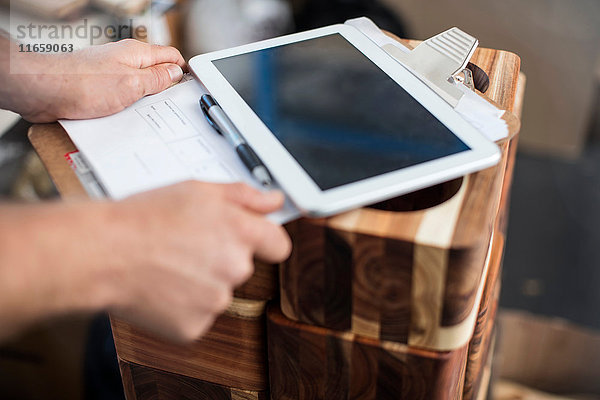 Mann benutzt digitales Tablett zur Kontrolle von Holzprodukten in der Fabrik