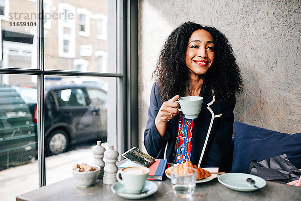 Mittlere erwachsene Frau mit Kaffeetasse im Cafe