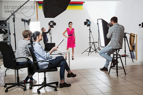 Fotografenteam und Modell beim Fotoshooting im Studio mit weißem Hintergrund