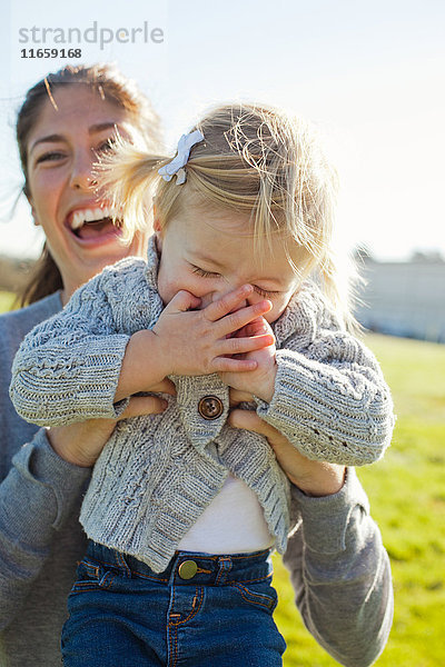 Weibliches Kleinkind wird von lachender Mutter aufgehalten