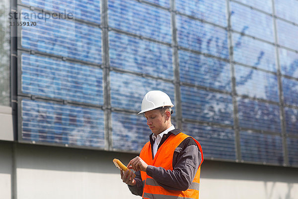 Männlicher Ingenieur benutzt Multimeter auf Solarzellenplatten