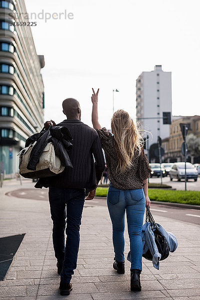 Rückansicht des jungen Paares beim Friedensschild auf dem Bürgersteig der Stadt