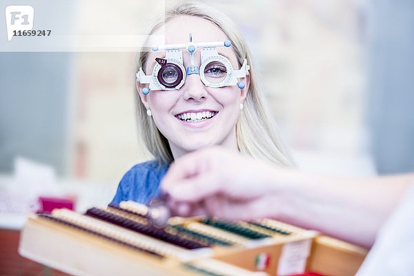 Porträt einer fröhlichen jungen Frau  die in einem Optikergeschäft eine Probefassung trägt  Nahaufnahme.