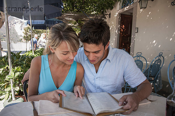 Ehepaar betrachtet Speisekarte im Restaurant im Freien  Lago Maggiore  Italien
