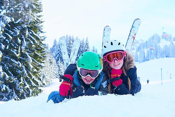 Porträt einer Ski fahrenden Teenagerin und ihres Bruders im Schnee liegend  Gstaad  Schweiz