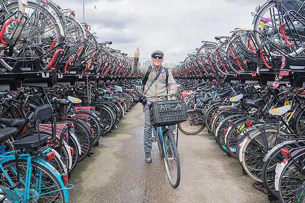 Radfahrer auf dem Fahrrad  der in die Kamera schaut und den Daumen hochhebt  Amsterdam  Niederlande