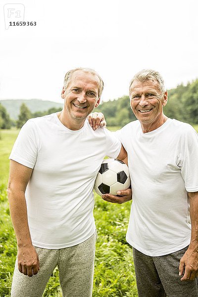 Zwei Männer  die die Arme umeinander legen und einen Fußball halten.