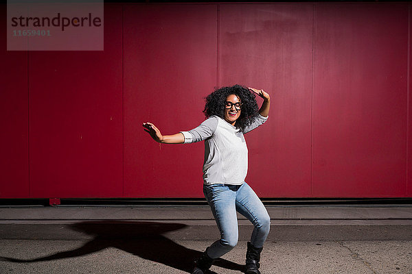 Porträt einer Frau  die vor einer roten Wand tanzt