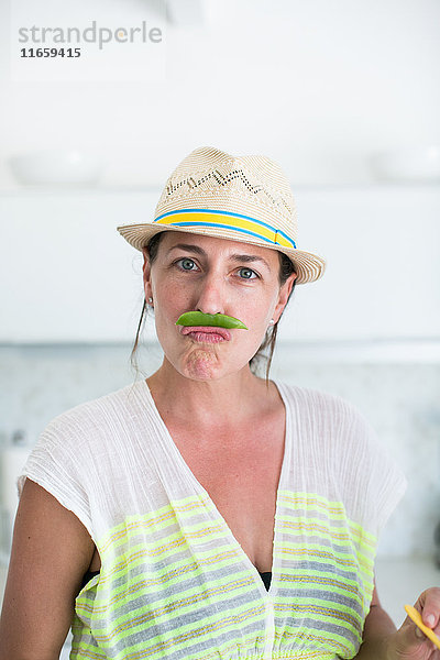 Bildnis einer mittelgroßen erwachsenen Frau mit Strohhut und Schnurrbart aus Erbsenschoten