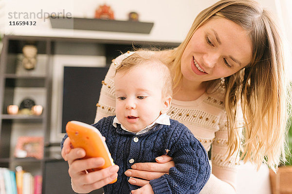 Mutter hält Baby mit Spielzeug-Smartphone