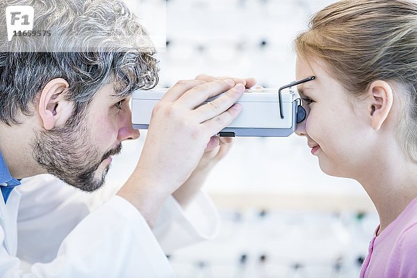 Ein Optiker führt einen Sehtest bei einem jungen Mädchen durch.