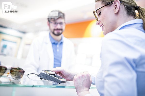 Frau zahlt mit Kreditkarte in einem Optikergeschäft.