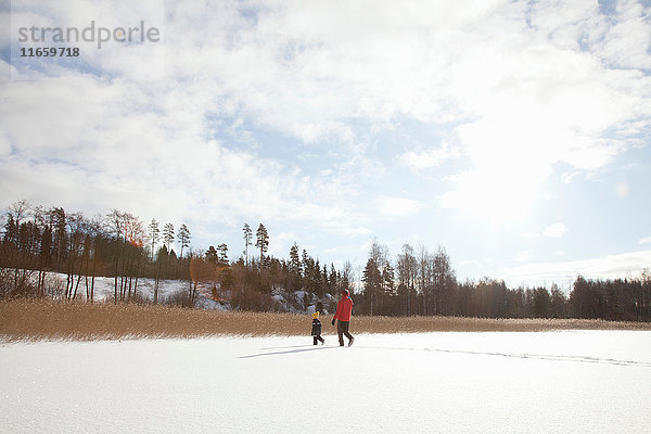 Vater und zwei Söhne wandern durch verschneite Landschaft
