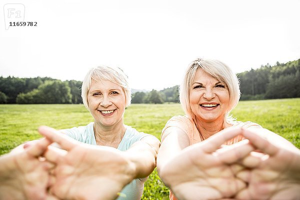 Zwei Frauen trainieren mit ausgestreckten Armen.