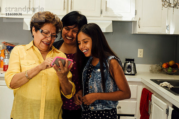 Mehrgenerationen-Familie sieht Smartphone lächelnd an