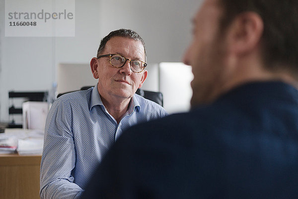 Männliche Kollegen in Diskussion am Büroschreibtisch