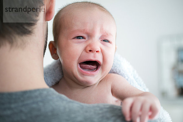 Über-Schulter-Ansicht eines Mannes  der ein weinendes Baby trägt