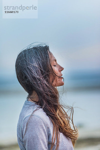 Profil einer reifen Frau im Freien  Augen geschlossen  Wind wehendes Haar