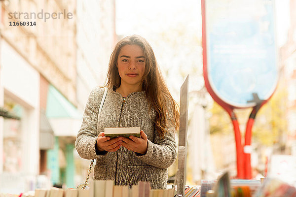 Porträt einer jungen Frau mit Buch in der Hand am Marktstand
