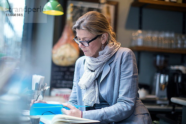 Reife Geschäftsfrau beim Papierkram im Restaurant