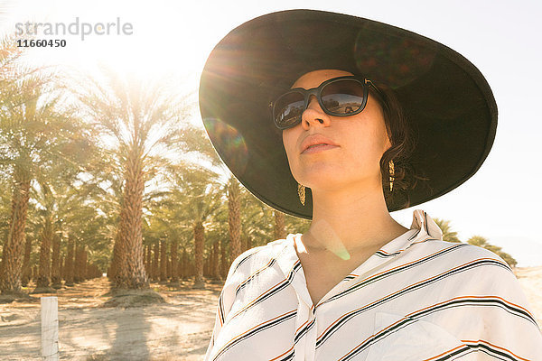 Porträt einer Frau mit Sonnenbrille und Sonnenhut beim Wegschauen  Palm Springs  Kalifornien  USA