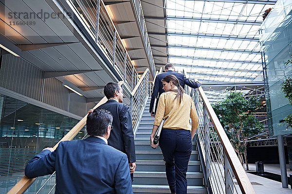 Rückansicht der Geschäftsfrau und der Männer  die die Bürotreppe hinaufgehen