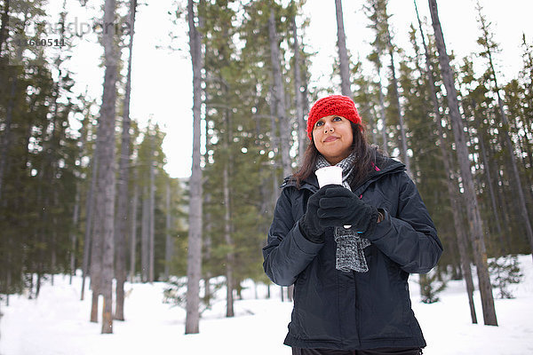 Frau am schneebedeckten Wald mit heißem Getränk in der Hand  Banff  Kanada
