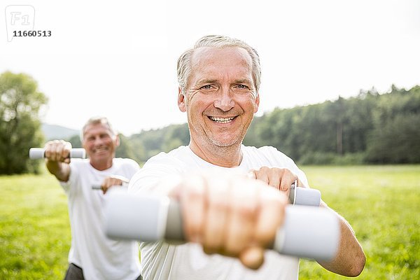 Zwei Männer trainieren mit Handgewichten.