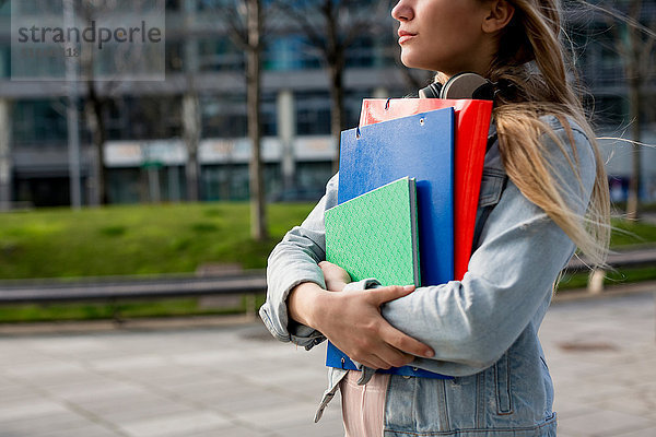 Junge Frau  Spaziergang im Freien  mit Aktenordner und Notizbuch  Mittelteil