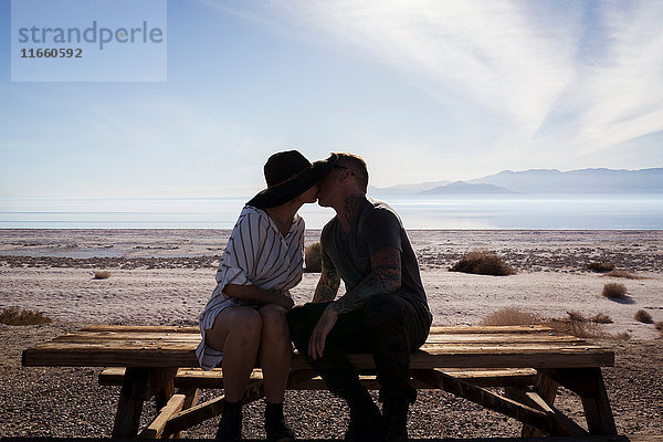 Paar  das auf einer Picknickbank sitzt und sich küsst  Salton Sea  Kalifornien  USA