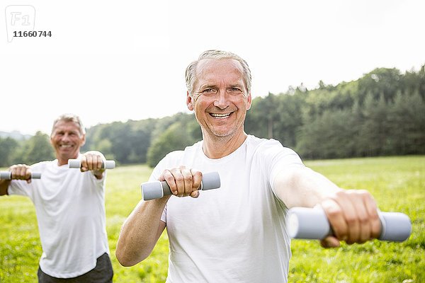 Zwei Männer trainieren mit Handgewichten.